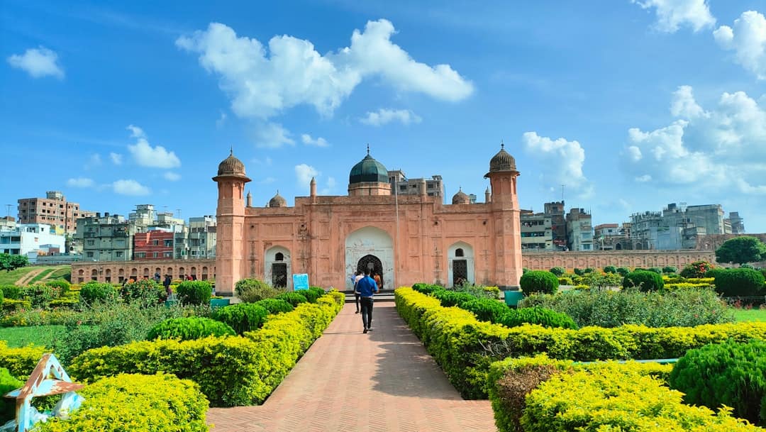 Photo by Motiur Rahman Shakil a person walking on a path in front of a large building